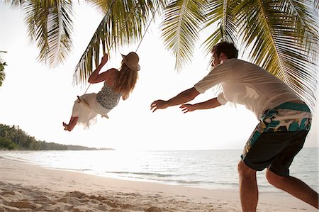 palm woman beach - Man pushing swinging woman at beach Stock Photo - Premium Royalty-Free, Code: 649-03881292