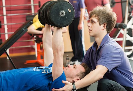 Trainer helping man lift weights at gym Foto de stock - Sin royalties Premium, Código: 649-03881971
