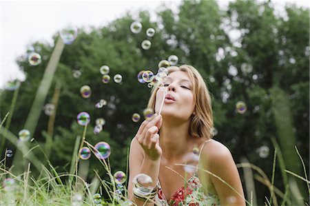 Woman blowing bubbles in field Foto de stock - Sin royalties Premium, Código: 649-03882401