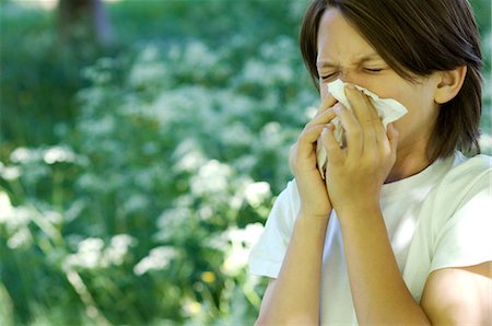 Boy blowing his nose in field of flowers Stock Photo - Premium Royalty-Free, Code: 649-03883614