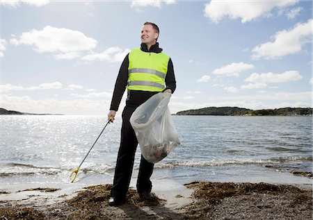 people picking up trash - Worker in safety vest cleaning beach Stock Photo - Premium Royalty-Free, Code: 649-03883630