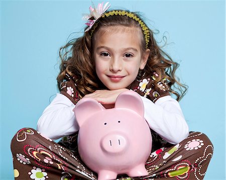 Girl (8-9) sitting with piggybank, studio shot Stock Photo - Premium Royalty-Free, Code: 640-05760829