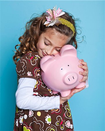 Girl (8-9) embracing piggybank, studio shot Stock Photo - Premium Royalty-Free, Code: 640-05760831