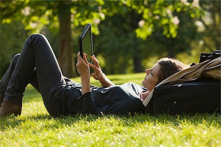 UK, London, Woman lying on grass using tablet Stock Photo - Premium Royalty-Free, Code: 640-05760871