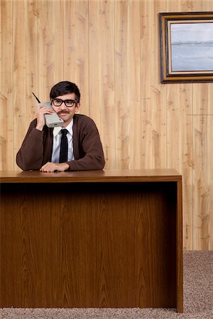 person talking old fashioned phone - Businessman using old fashioned mobile phone in office Stock Photo - Premium Royalty-Free, Code: 640-05761195