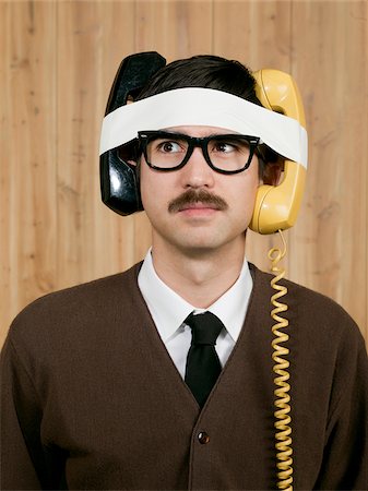 Businessman with telephones strapped to head in office Stock Photo - Premium Royalty-Free, Code: 640-05761208