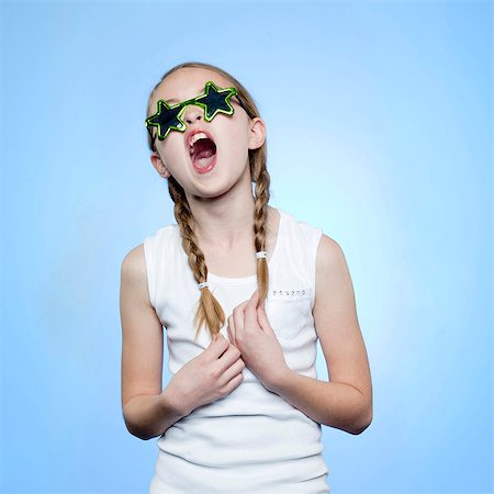 Studio portrait of girl (10-11) wearing star shaped glasses singing Foto de stock - Royalty Free Premium, Número: 640-05761257