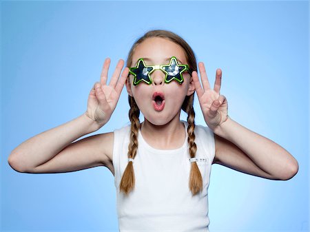 Studio portrait of girl (10-11) wearing star shaped glasses cheering Stock Photo - Premium Royalty-Free, Code: 640-05761258