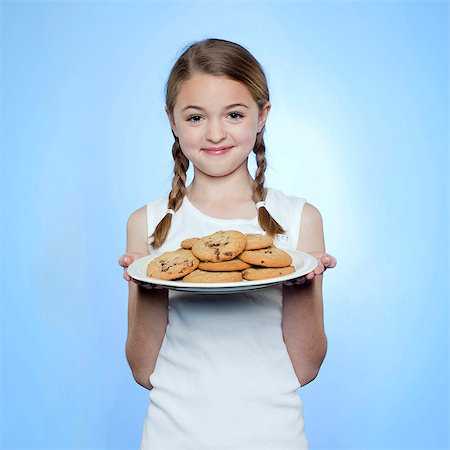 Studio portrait of girl (10-11) holding cookies on plate Stock Photo - Premium Royalty-Free, Code: 640-05761261