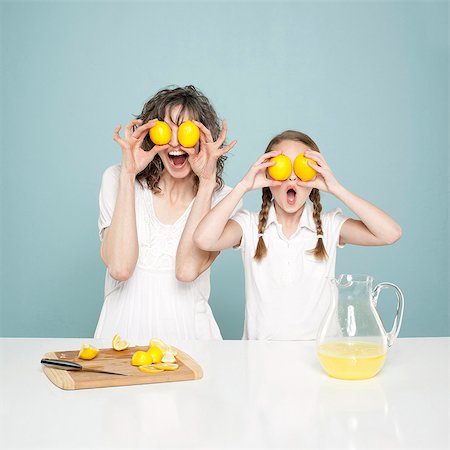 fruit stand - Studio shot of mother and daughter (10-11) holding lemons, fooling around Stock Photo - Premium Royalty-Free, Code: 640-05761276