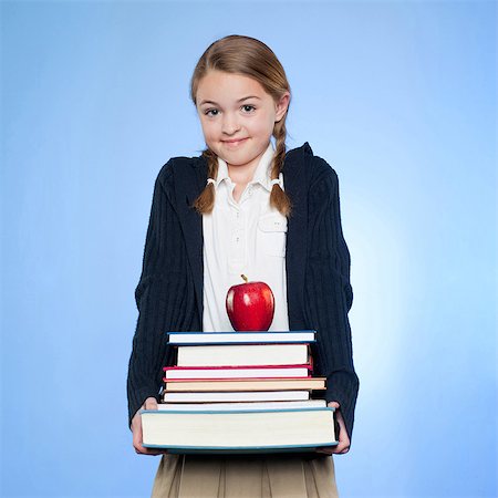 Studio portrait of girl (10-11) holding stack of books and apple Stock Photo - Premium Royalty-Free, Code: 640-05761270