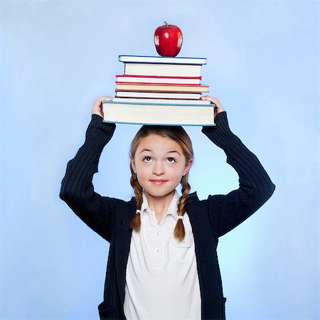 sage - Studio coup de jeune fille (10-11) pile de tenue de livres et de pomme sur la tête Photographie de stock - Premium Libres de Droits, Code: 640-05761271