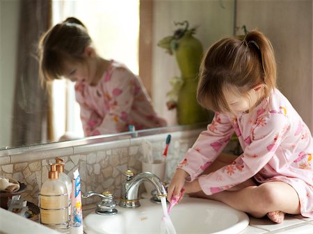 USA, Utah, Cedar Hills, Girl (4-5) sitting by bathroom sink, rinsing toothbrush Stock Photo - Premium Royalty-Free, Code: 640-05761316