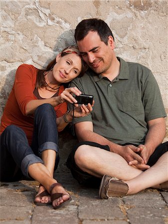 Italy, Venice, Couple viewing digital camera by wall Stock Photo - Premium Royalty-Free, Code: 640-06049840