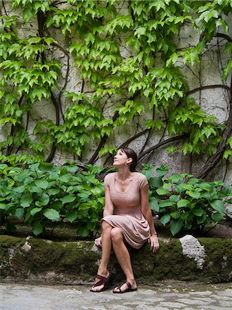 Italy, Ravello, Portrait of woman in dress sitting in front of overgrown wall Foto de stock - Sin royalties Premium, Código: 640-06050027