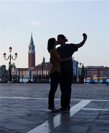 Italy, Venice, Young couple kissing and photographing self, San Giorgio Maggiore church in background Foto de stock - Sin royalties Premium, Código: 640-06050270