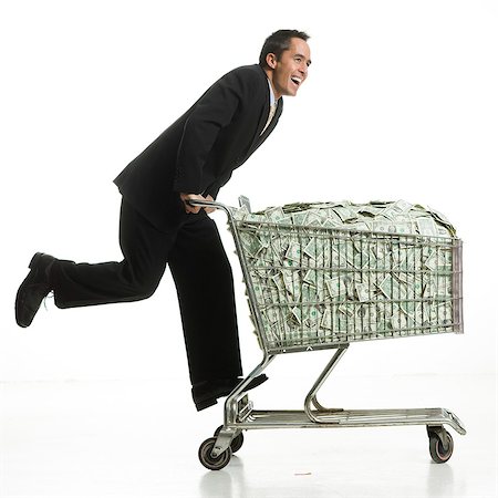 businessperson with a shopping cart full of money Stock Photo - Premium Royalty-Free, Code: 640-06051205