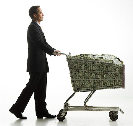 businessperson with a shopping cart full of money Stock Photo - Premium Royalty-Free, Code: 640-06051206