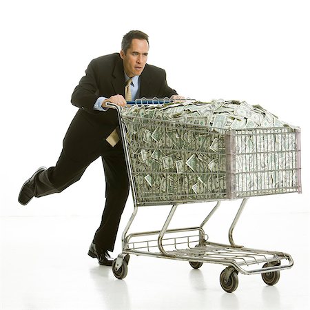 businessperson with a shopping cart full of money Stock Photo - Premium Royalty-Free, Code: 640-06051217