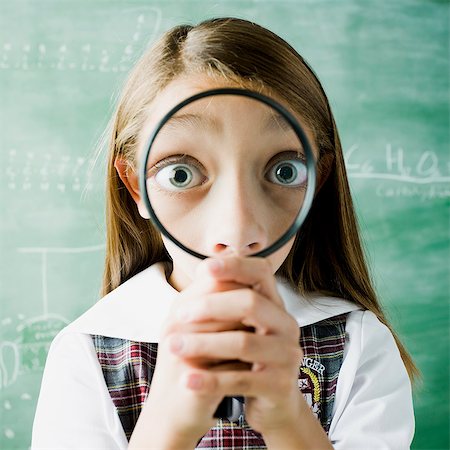 girl in a classroom smiling through a magnifying glass Foto de stock - Sin royalties Premium, Código: 640-06051650