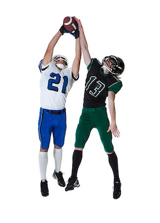 Two male players of American football catching ball, studio shot Stock Photo - Premium Royalty-Free, Code: 640-06963162