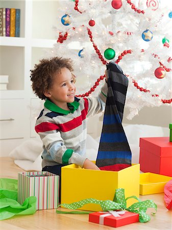 Young boy sitting under Christmas tree, opening Christmas presents Stock Photo - Premium Royalty-Free, Code: 640-06963459