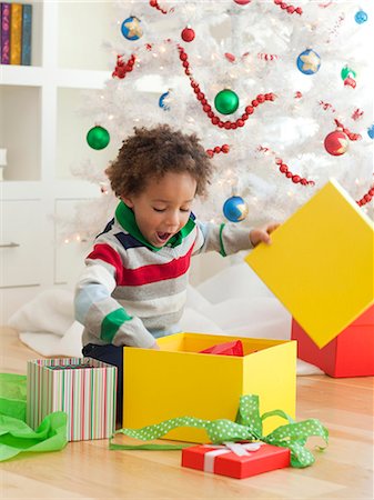 simsearch:640-02949371,k - Young boy sitting under Christmas tree, opening Christmas presents Stock Photo - Premium Royalty-Free, Code: 640-06963460