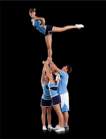 Studio shot of cheerleaders (16-17) supporting friend standing on one leg Photographie de stock - Premium Libres de Droits, Code: 640-06963637