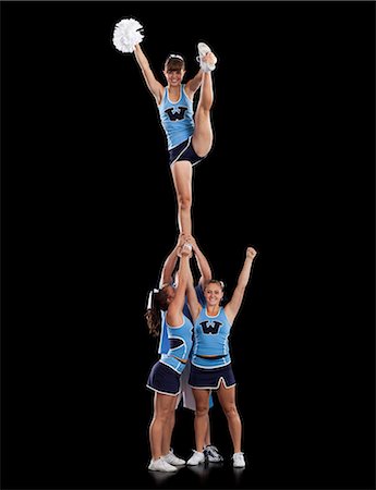 Studio shot of cheerleaders (16-17) supporting friend standing on one leg Stock Photo - Premium Royalty-Free, Code: 640-06963638