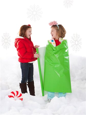 simsearch:640-02953389,k - Studio shot of girl (4-5) wrapping friend (6-7) as Christmas gifts Photographie de stock - Premium Libres de Droits, Code: 640-06963715