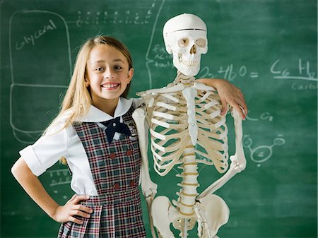 girl in a classroom standing in front of a chalkboard with a human skeleton Stock Photo - Premium Royalty-Free, Code: 640-08089207