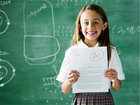 girl in a classroom standing in front of a chalkboard with an a plus paper Foto de stock - Sin royalties Premium, Código: 640-08089208