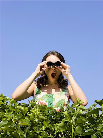 woman looking over a hedge with binoculars Foto de stock - Sin royalties Premium, Código: 640-08089607