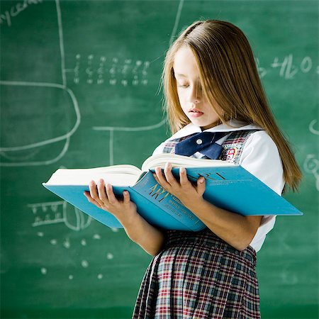 simsearch:6109-06196569,k - girl in a classroom standing in front of a chalkboard holding a book Foto de stock - Sin royalties Premium, Código: 640-08089696