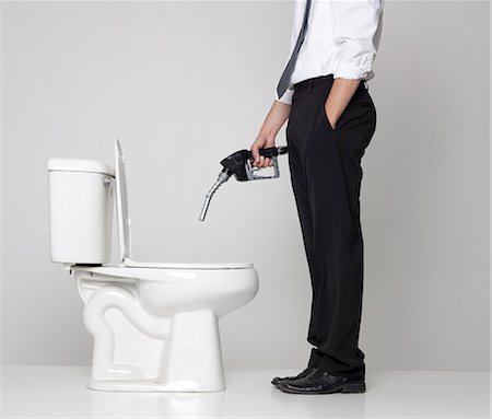 Studio shot of businessman pouring fuel into toilet Stock Photo - Premium Royalty-Free, Code: 640-08546045