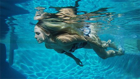 simsearch:640-06963281,k - Underwater view of woman in bikini swimming in pool Photographie de stock - Premium Libres de Droits, Code: 640-09013380