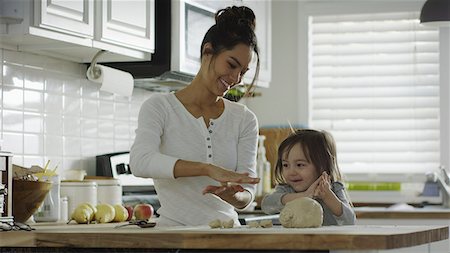 relaxing in the kitchen - Smiling mother teaching daughter to bake and roll dough in kitchen Stock Photo - Premium Royalty-Free, Code: 640-09013400