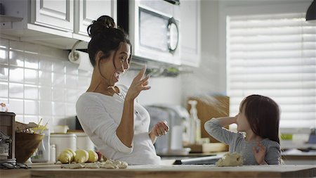 Blurred playful mother and daughter baking and tossing dough in kitchen Foto de stock - Sin royalties Premium, Código: 640-09013401