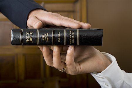 Close-up of a witnesses hand swearing over the Bible Stock Photo - Premium Royalty-Free, Code: 640-01348414