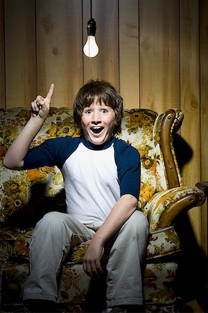 Boy sitting on sofa with light bulb idea Foto de stock - Sin royalties Premium, Código: 640-01348527