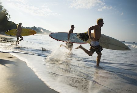 photos manuel antonio national park - Profile of a mid adult couple and a young man running on the beach with surfboards Stock Photo - Premium Royalty-Free, Code: 640-01348529