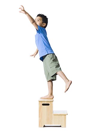 Boy standing on wooden step reaching Stock Photo - Premium Royalty-Free, Code: 640-01348564