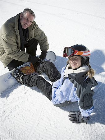 High angle view of a father helping his daughter put on a snowboard Stock Photo - Premium Royalty-Free, Code: 640-01348612