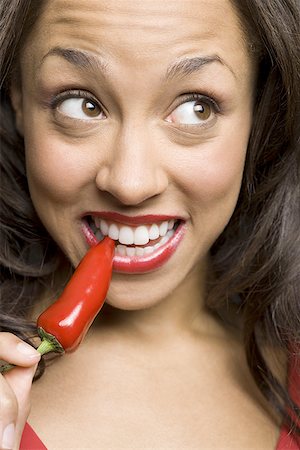 person with hot pepper - Close-up of a young woman biting a red chili pepper Stock Photo - Premium Royalty-Free, Code: 640-01348747