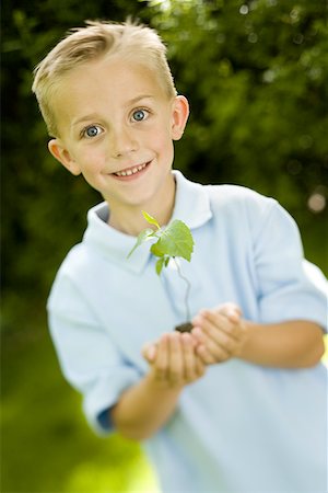 Portrait of a child holding a plant sapling Stock Photo - Premium Royalty-Free, Code: 640-01348798