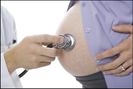 Close-up of a doctor's hand examining a pregnant woman with a stethoscope Stock Photo - Premium Royalty-Free, Code: 640-01348853