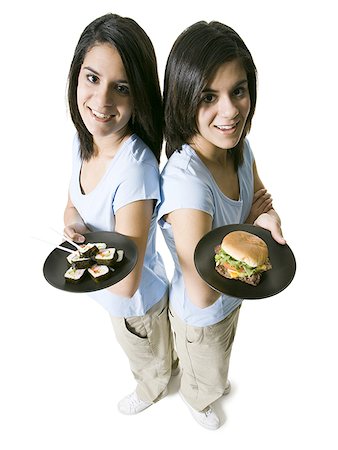 High angle view of two teenage girls holding plates of food Stock Photo - Premium Royalty-Free, Code: 640-01349106