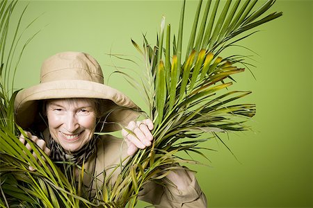 simsearch:640-01351888,k - Portrait of an elderly woman smiling between palm leaves Foto de stock - Royalty Free Premium, Número: 640-01349226