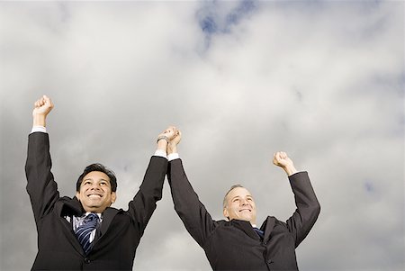 Low angle view of two businessmen standing with their arm raised Stock Photo - Premium Royalty-Free, Code: 640-01349253