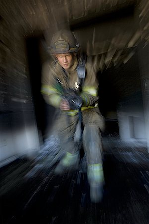 disaster and rescue - Portrait of a firefighter holding a fire hose Foto de stock - Sin royalties Premium, Código: 640-01349296